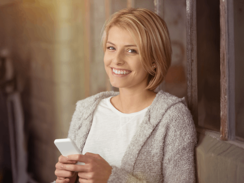 lachende Frau mit Smartphone in der Hand