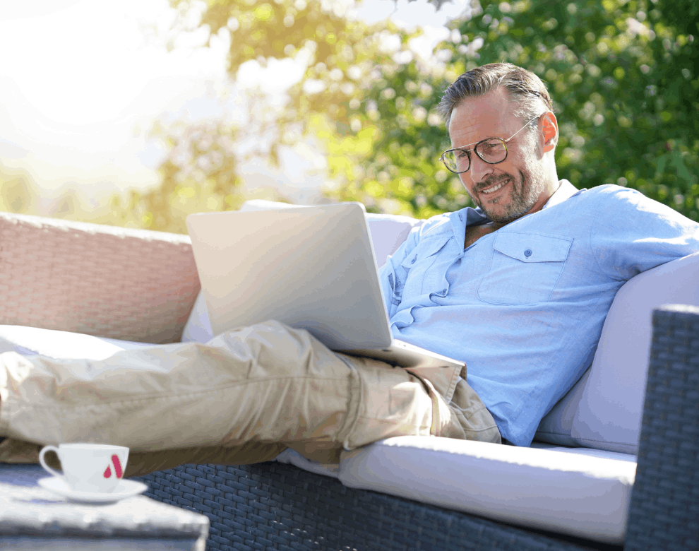 Mann, der entspannt mit Laptop auf Terrasse sitzt
